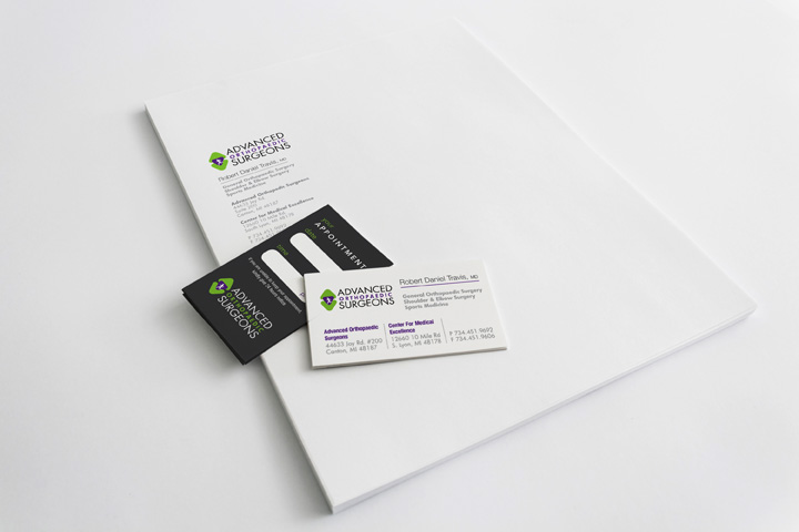 A business card is sitting on top of a white sheet of paper.