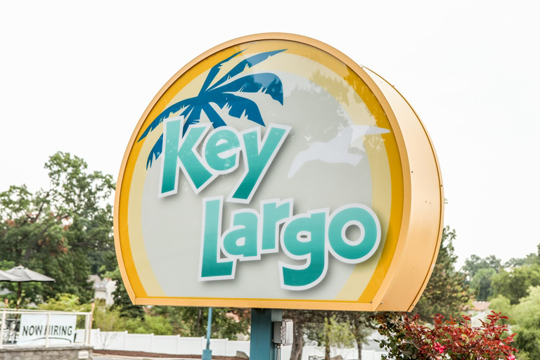 A sign that says key largo in front of a palm tree.